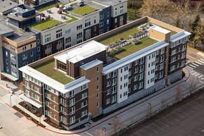 Kirkland apartment for rent - A large building with a green roof is surrounded by a parking lot.