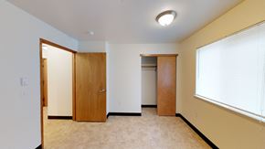 Bellingham apartment for rent - A room with a carpeted floor, a window with blinds, and a wooden door.