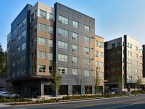Kirkland apartment for rent - A modern multi-story building with a mix of dark and light brown panels.