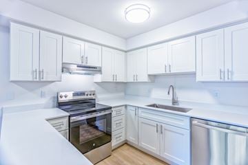Bellingham apartment for rent - A white kitchen with a stove, sink, and cabinets.