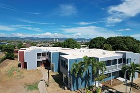 Waipahu apartment for rent - A blue and red building with a white roof and a green lawn in front.