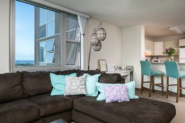 Honolulu apartment for rent - a living room with a couch and a kitchen with a table and chairs
