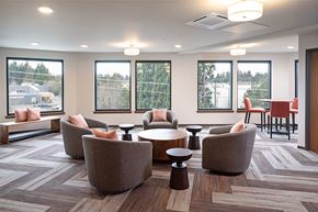 Lynnwood apartment for rent - a lounge area with chairs and tables in a room with windows