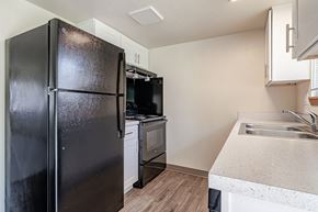 Ellensburg apartment for rent - A black refrigerator stands in a kitchen with a sink and stove.