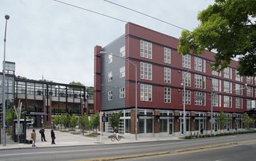 Seattle apartment for rent - A red building with a glass entrance and a street in front.