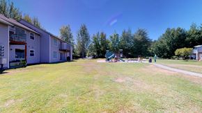 Bellingham apartment for rent - A sunny day at the park with a playground and apartment buildings in the background.