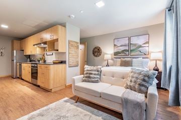 Bothell apartment for rent - A modern living room with a white couch and a kitchen area in the background.