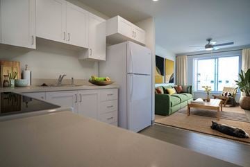Kapolei apartment for rent - A kitchen with white cabinets and a green couch in the living room.