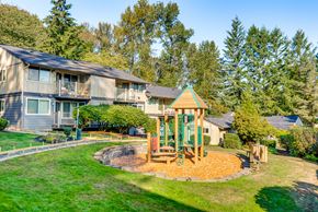 Issaquah apartment for rent - A playground with a green swing set is in the foreground of a grassy area.