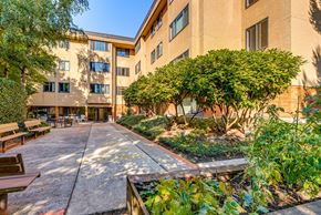 Mercer Island apartment for rent - A courtyard with a bench and a tree in front of a building.