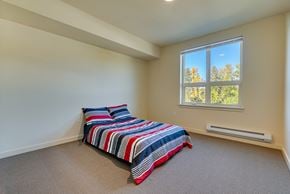 Kirkland apartment for rent - A bedroom with a bed and a window overlooking trees.
