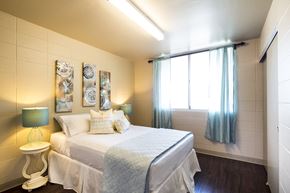 Honolulu apartment for rent - A bedroom with a bed, a nightstand with a lamp, and a window with curtains.