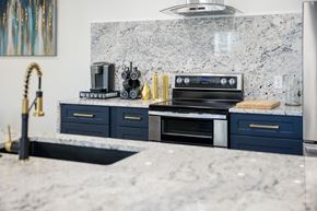 Vernal apartment for rent - A kitchen with a marble countertop and dark blue drawers.