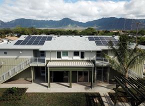 Walanae apartment for rent - A house with solar panels on the roof and a mountain range in the background.