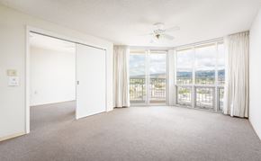 Honolulu apartment for rent - an empty living room with a ceiling fan and large windows