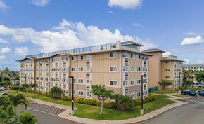 Kapolei apartment for rent - a large apartment building with a parking lot and palm trees
