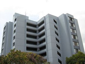 Honolulu apartment for rent - a large white building with trees in front of it