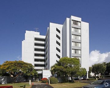 Honolulu apartment for rent - a tall white building with trees in front of it