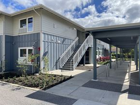 Walanae apartment for rent - A modern building with a grey and blue exterior and a covered walkway.