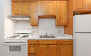Honolulu apartment for rent - A kitchen with wooden cabinets and a white stove top oven.