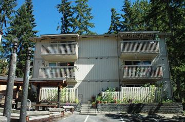 Redmond apartment for rent - A large white building with balconies and a wooden deck in front.