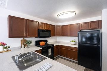 San Diego apartment for rent - A kitchen with brown cabinets and a black refrigerator.