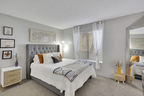 Denver apartment for rent - A bedroom with a large bed and a mirror on the wall.
