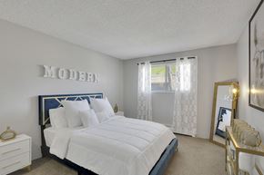 Denver apartment for rent - A bedroom with a large bed and a mirror on the wall.