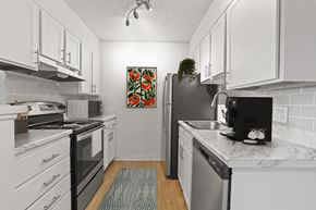 Denver apartment for rent - A kitchen with white cabinets and a black fridge.