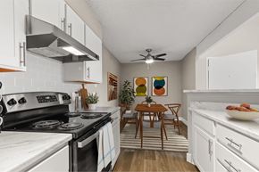 Denver apartment for rent - A kitchen with a stove top oven and a table with chairs.