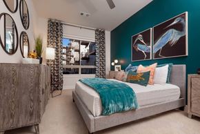Denver apartment for rent - A bedroom with a bed, a dresser, and a mirror on the wall.