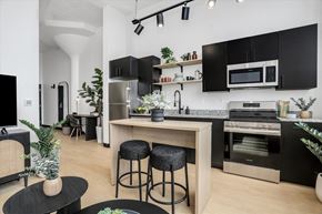 Detroit apartment for rent - a kitchen with black cabinets and a counter with two stools