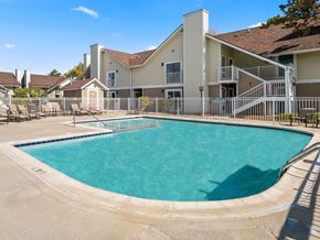Madison Heights apartment for rent - A swimming pool in front of a building with a white fence around it.