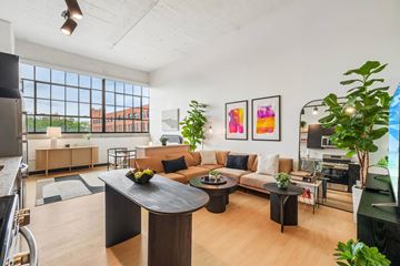 Detroit apartment for rent - A modern living room with a black coffee table and a large window.