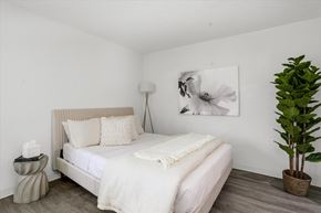Detroit apartment for rent - a bedroom with a white bed and a large potted plant