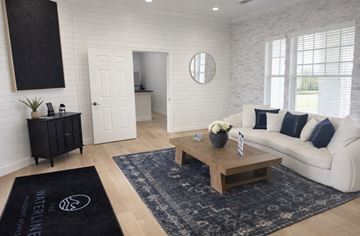 Gulfport apartment for rent - A living room with a white couch, a wooden coffee table, and a black rug with the text "WELINE" on it.