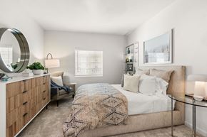 Peoria apartment for rent - A bedroom with a large bed and a dresser with a mirror.