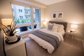 Detroit apartment for rent - A bedroom with a large bed and a window overlooking a building.
