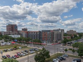 Detroit apartment for rent - A parking lot with cars and a large building in the background.