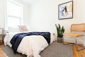 Detroit apartment for rent - a bedroom with a bed and a plant and a window