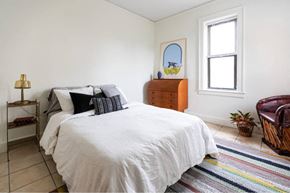 Detroit apartment for rent - A bedroom with a white bed and a wooden dresser.