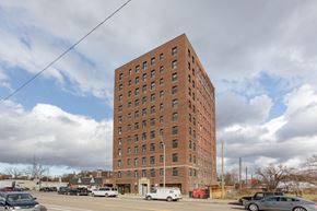 Detroit apartment for rent - a tall brick building with cars parked in a parking lot