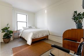 Detroit apartment for rent - a bedroom with a bed and a dresser and a potted plant