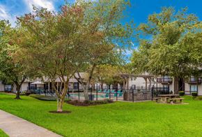 Ridgeland apartment for rent - a park with trees and a pool in front of a building