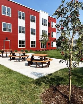 Austin apartment for rent - A tree with red flowers is planted in front of a red and white building.