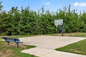 Jordan townhouse for rent - A basketball court surrounded by green trees and a bench.