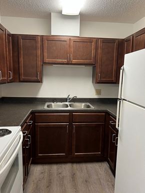 Crookston apartment for rent - a kitchen with dark wood cabinets and white appliances