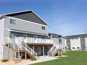 Mankato townhouse for rent - A grey and white apartment building with a balcony and stairs.