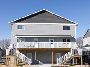 Mankato townhouse for rent - A two-story house with a balcony and stairs leading to the front door.