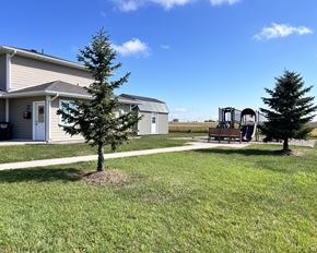 Eagle Lake townhouse for rent - A playground with a slide and swings is located in a grassy area in front of a building.